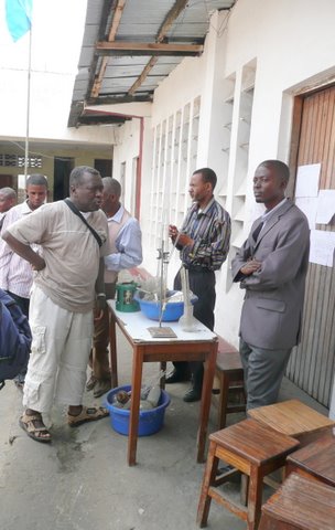 Dr. Kuyitila et l’enseignant de chimie et de biologie devant la « collection des sciences naturelles » de l’école G.SCO.M. Dr. Kuyitila et l’enseignant de chimie et de biologie devant la « collection des sciences naturelles » de l’école G.SCO.M.